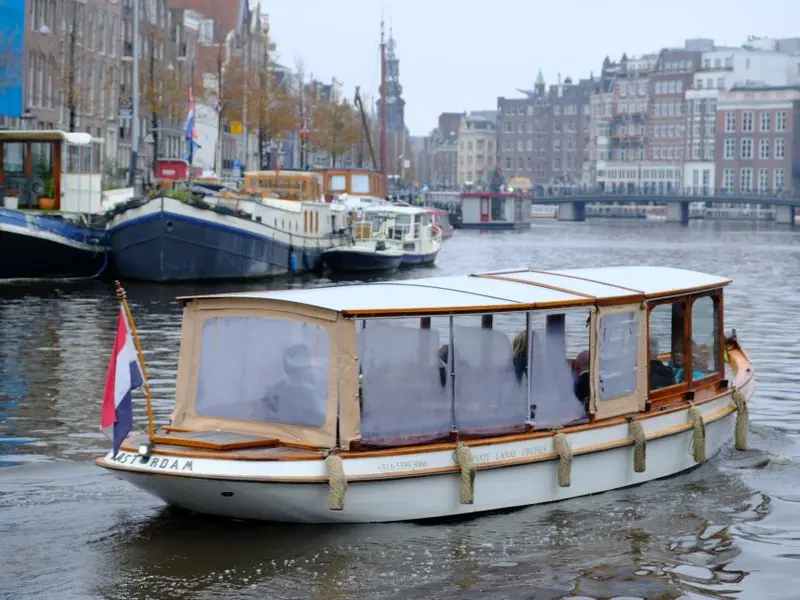 Sightseeing canal boat cruising past houseboats and canal houses in Amsterdam